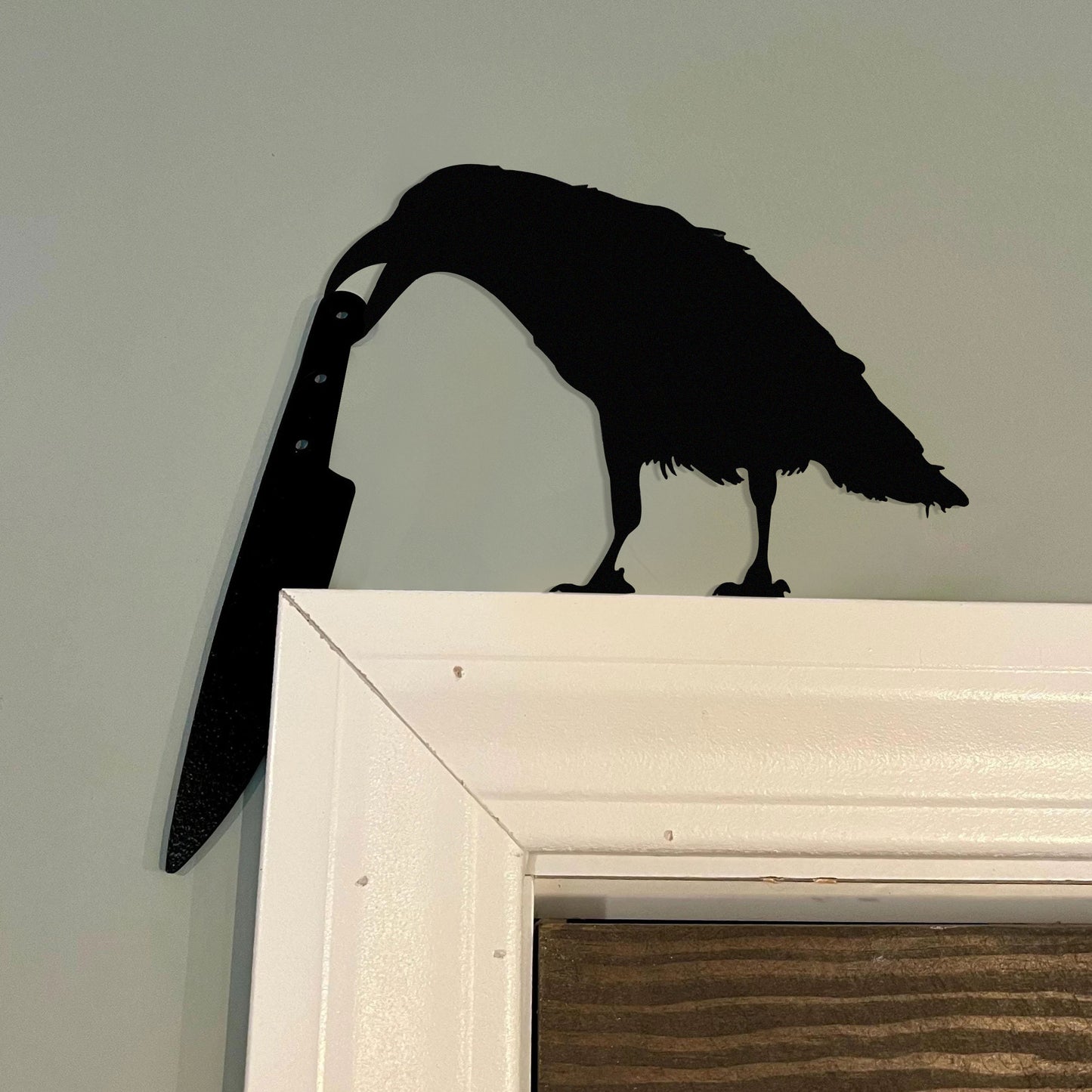 Raven holding a knife metal art