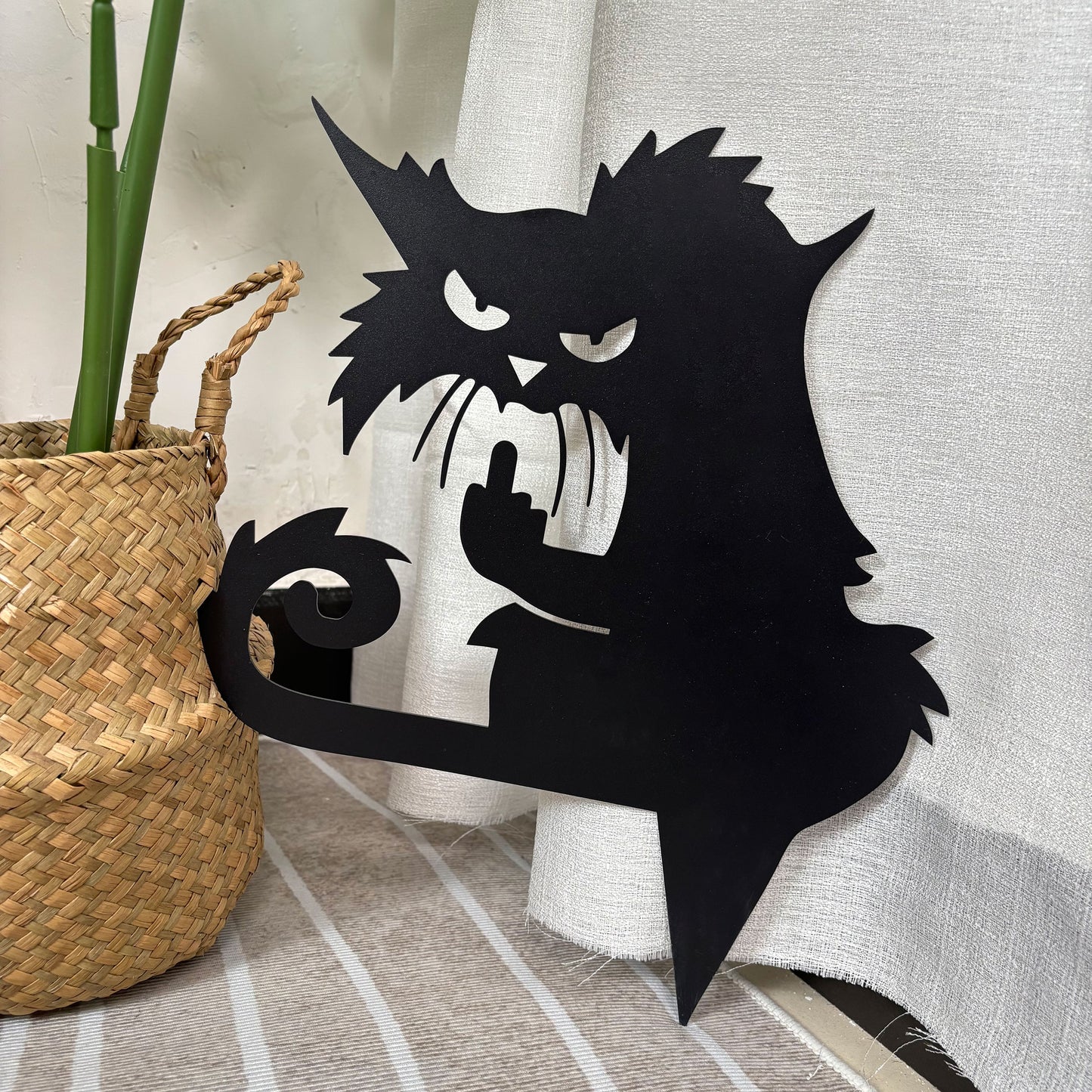 Metal art of a grumpy black cat giving the middle finger