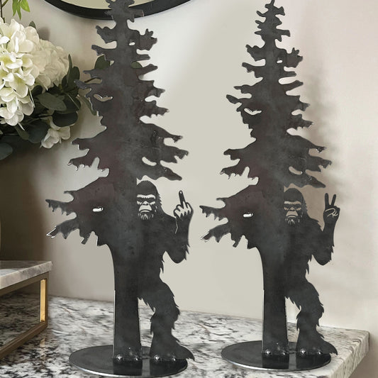 Bigfoot hiding behind an evergreen tree with his middle finger raised